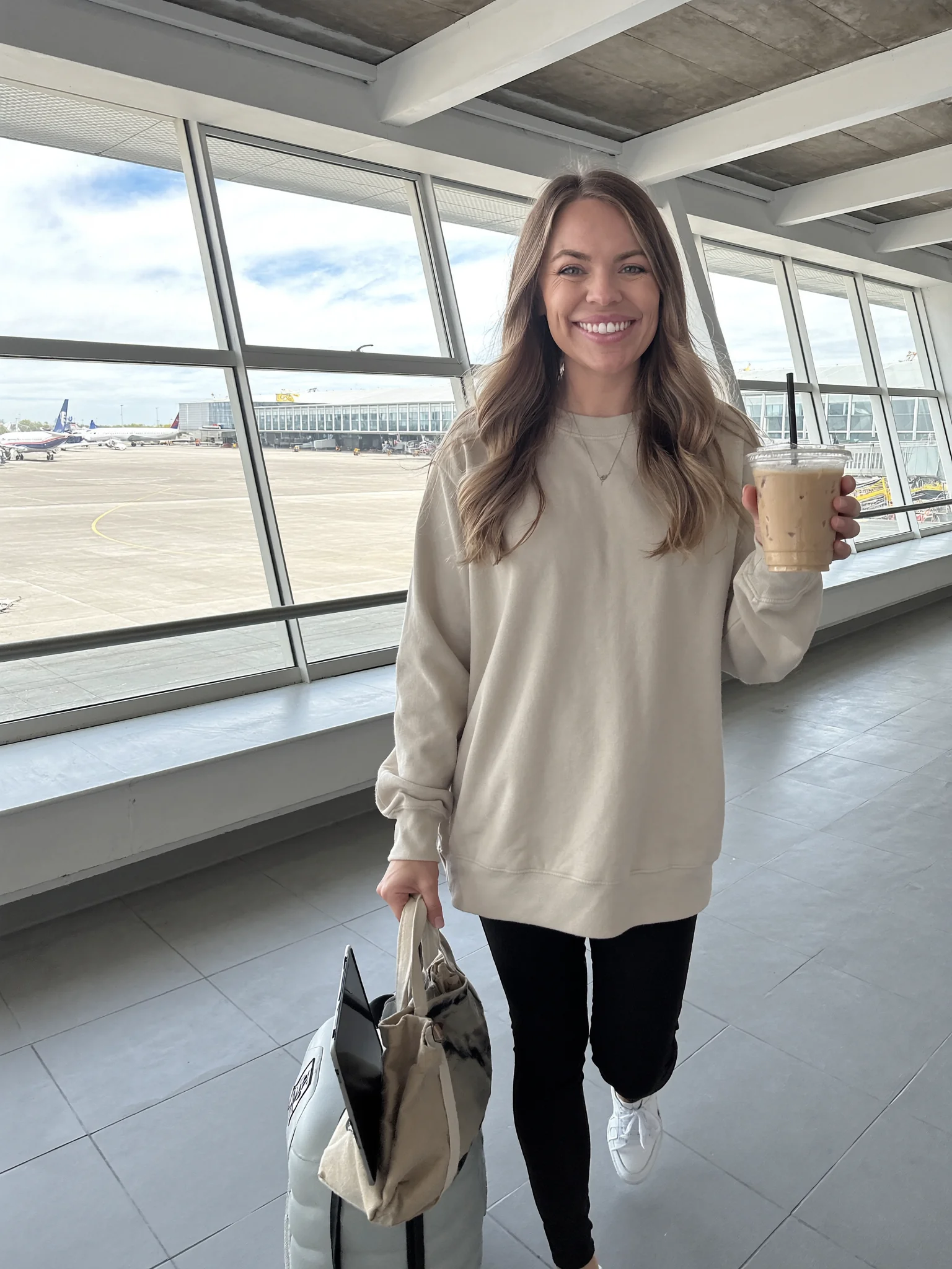 Arianna smiling at the airport with an iced coffee